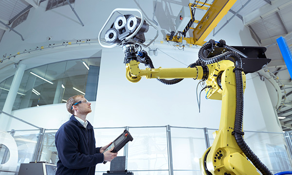 Person operating a robot in a digital manufacturing plant 