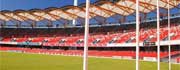 Inside of the Metricon Stadium showing posts, the pitch and red stadium seats Inside of the Metricon Stadium showing posts, the pitch and red stadium seats