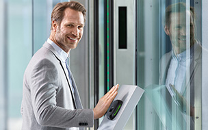 Photo of a smiling man in a suit using a PalmSecure scanner
