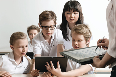 School children and teacher working with tablet computers
