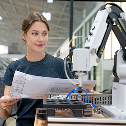 Engineer woman working with blueprints and robotic arm