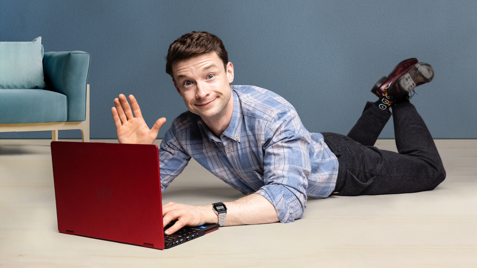 Brian lies behind the laptop and waves.