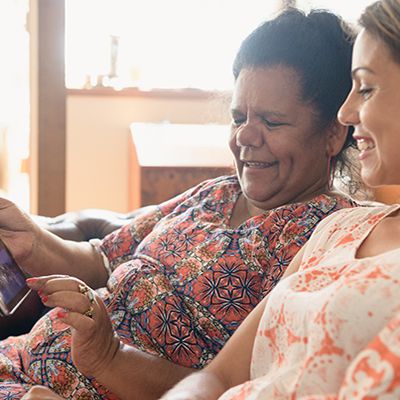 two-women-smiling-looking-at-tablet-device