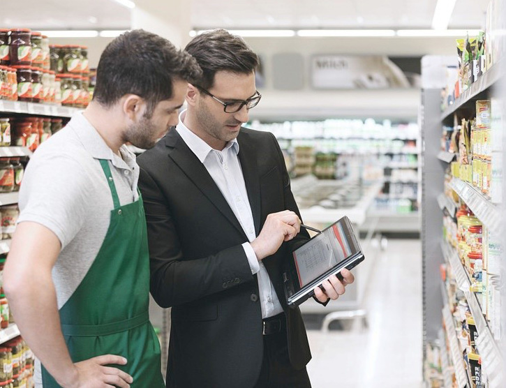 2 men checking stock data on a tablet in the supermarket