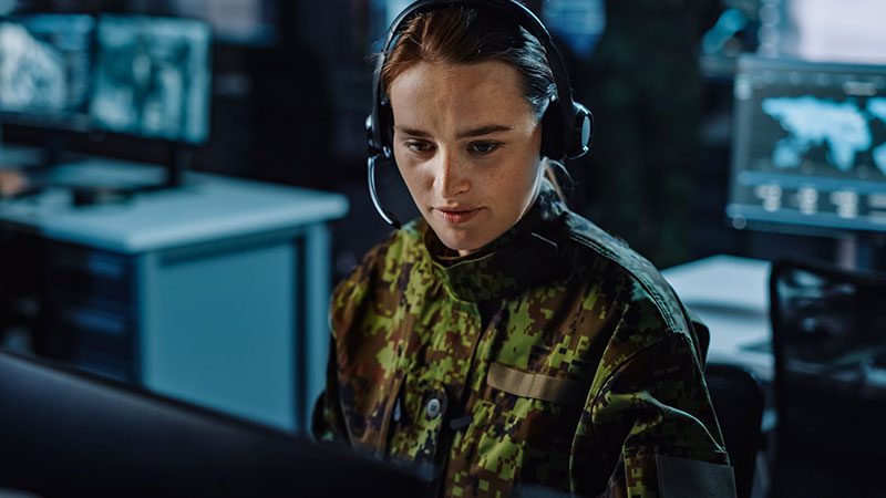 Eine Frau in Militäruniform arbeitet konzentriert an einem Computer.