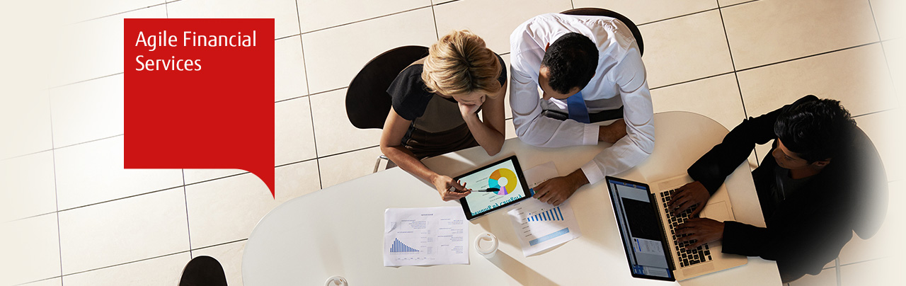 Photo from above of people working together using a tablet, printed graphs, a laptop.