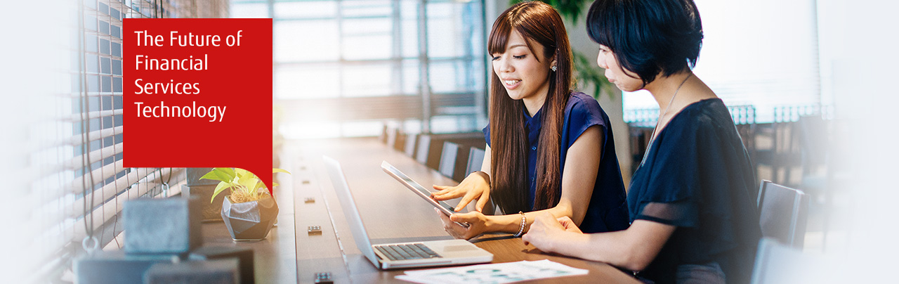 Photo of two women working together with a tablet and a laptop