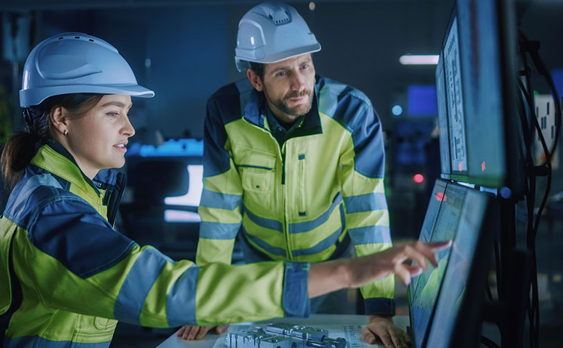 Ingenieur*innen in der Fabrik prüfen Produktionsdaten an Monitoren