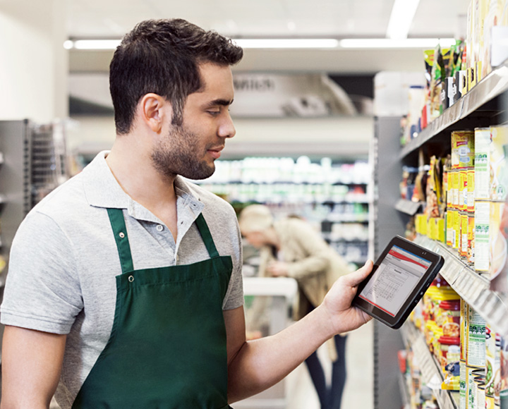 an employee checking stock levels on a tablet in a supermarket