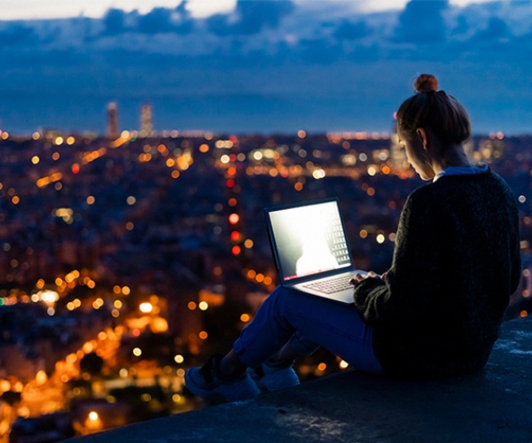 Junge Frau, die am Abend einen Laptop verwendet