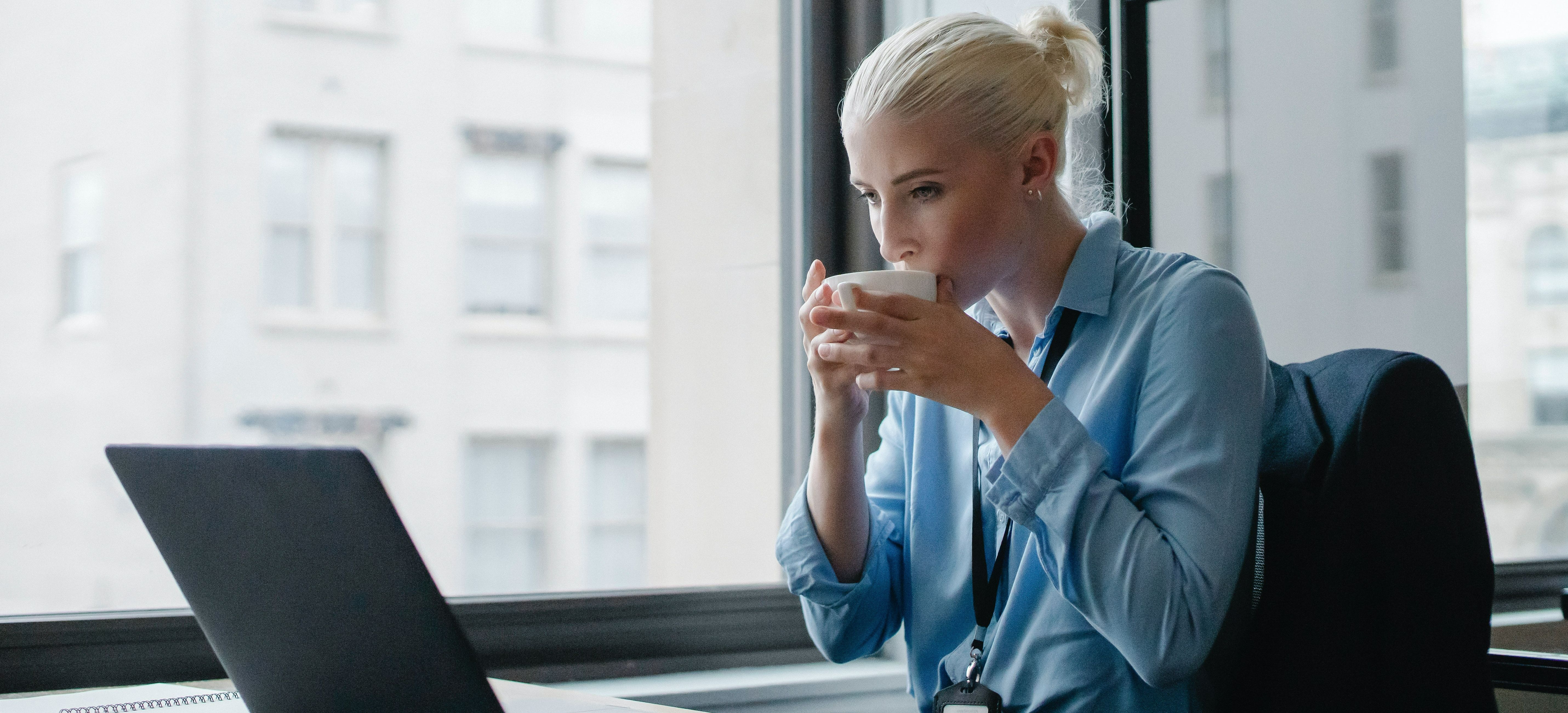 Woman drinking coffee and looking into computer screen
