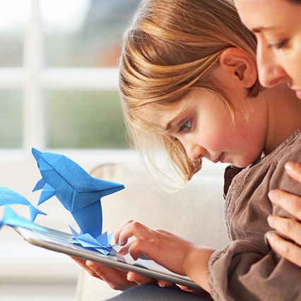 child using tablet with origami dolphins