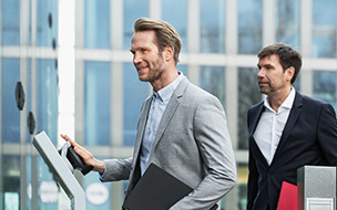 Photo of two men in suits using a PalmSecure scanner