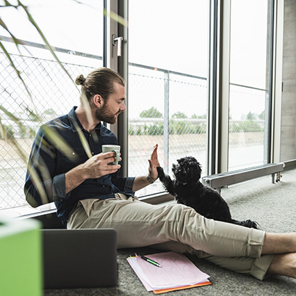 woman talking on phone using laptop next to origami apple and coffee