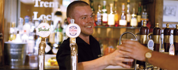 Barman passing a pint to a customer