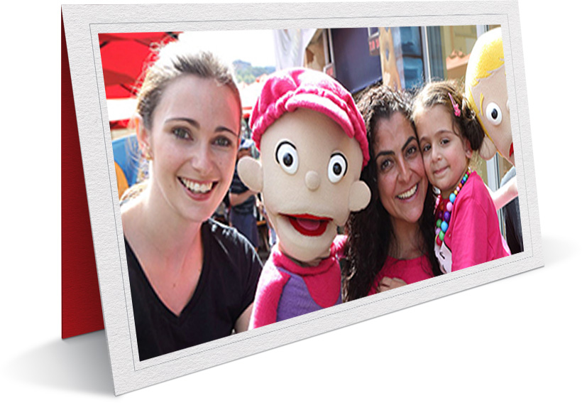 Photo of camp volunteers and their travelling puppets with children