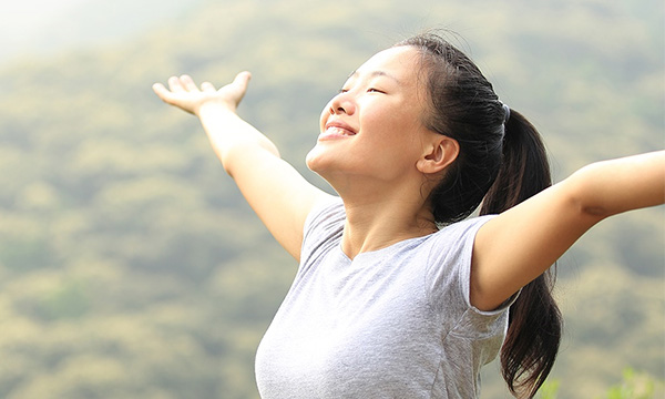 Woman in nature with outstretched arms.