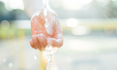 Hand under running water symbolizing a regenerative society.