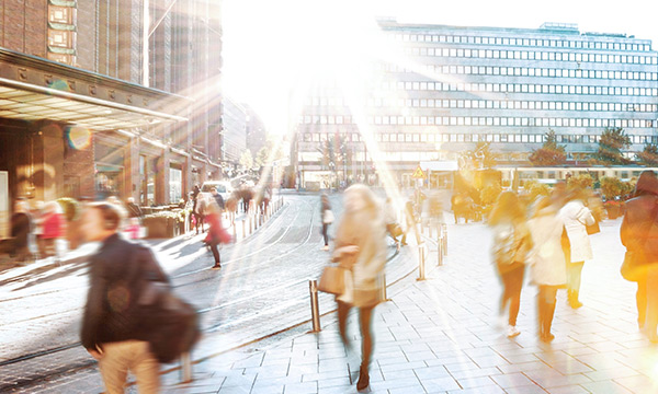 People walking in a city on a sunny day, symbolizing the transformation of business and society.