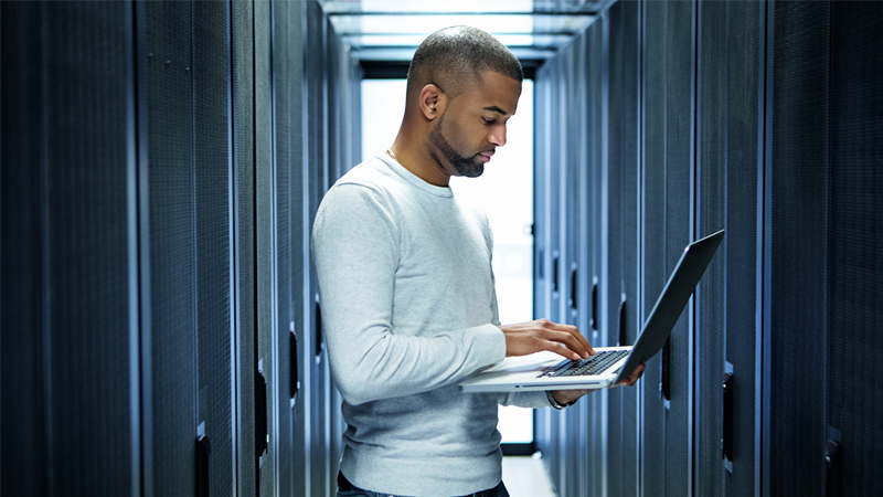 a person using a laptop in a server room