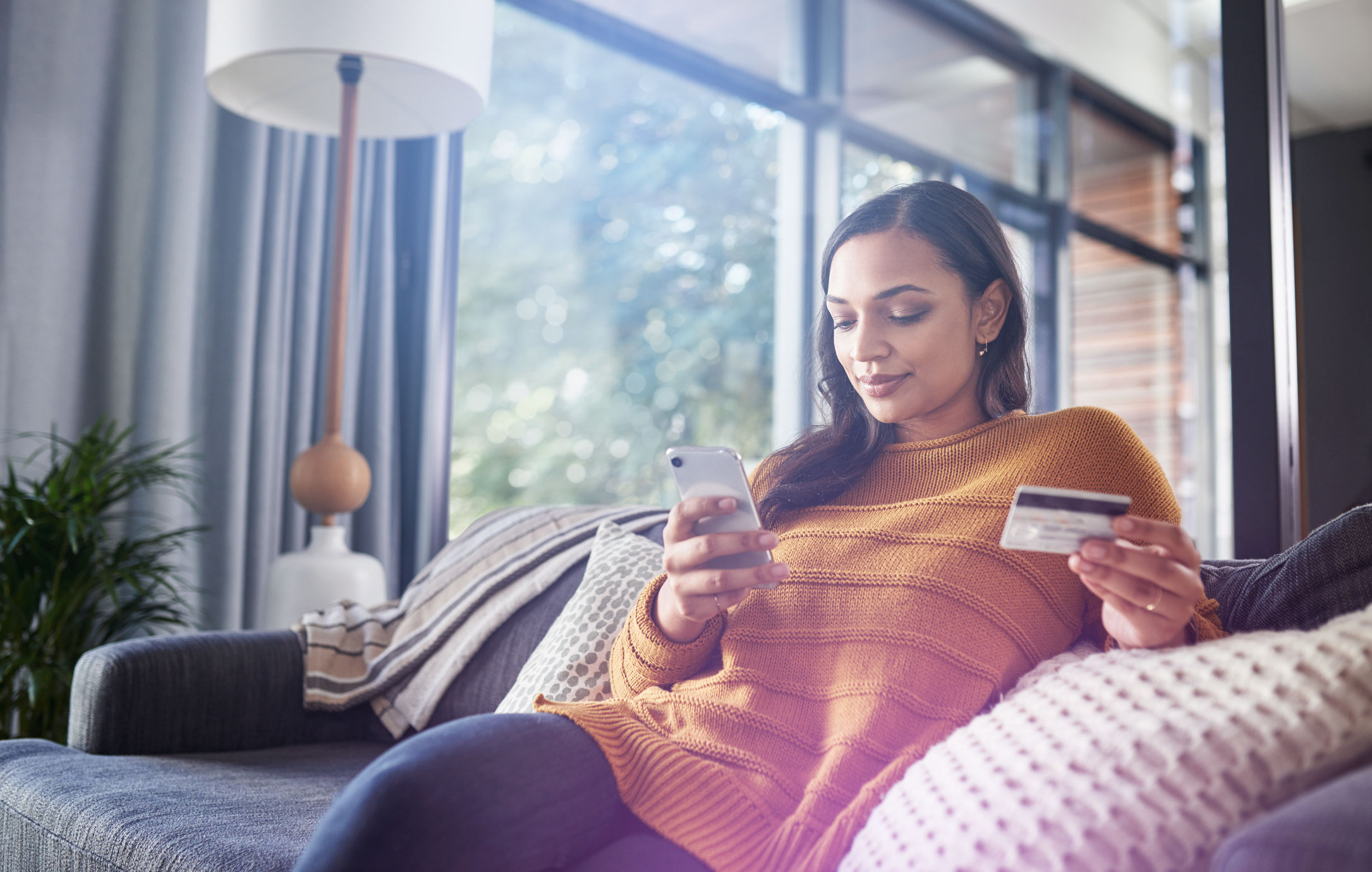 A woman makes a mobile payment from her sofa