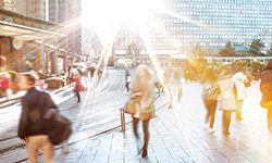 People walking in a city on a sunny day, symbolizing the transformation of business and society.