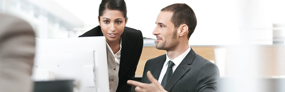 Man and a woman talking while looking at a computer screen