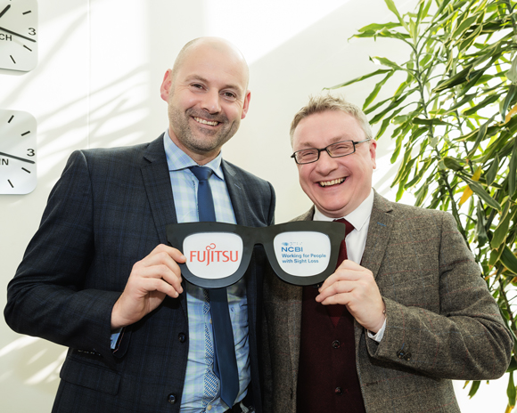 Tony O’Malley CEO Fujitsu Ireland on the left & Chris White, CEO of NCBI on the right, both are holding a pair of dummy glasses with the Fujitsu logo shown in one lens and the NCBI logo in the other lens. Tony O’Malley CEO Fujitsu Ireland on the left & Chris White, CEO of NCBI on the right, both are holding a pair of dummy glasses with the Fujitsu logo shown in one lens and the NCBI logo in the other lens.
