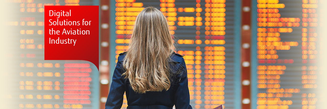 Photo of a woman looking at a flight information screen at an airport