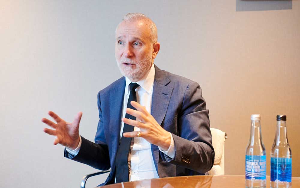 ミネラルウォーターのガラス瓶2本をテーブルに置き、語るポール氏