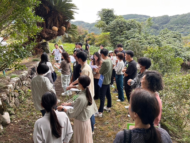 山中のような場所を、地元住民と一緒に散策するワーケーション参加者たち