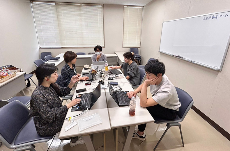 5名が部屋の中でPCを使いながら打合せしている様子