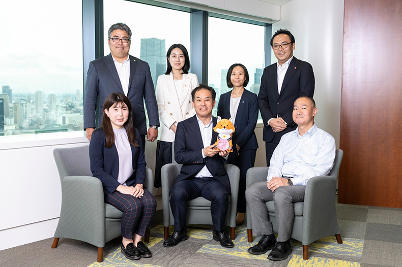 画面下 法務省 民事局民事第二課 藤田課長(中央)、所有者不明土地等対策推進室 山本室長(右)、光木係長(左)画面中央ぬいぐるみ 不動産登記推進イメージキャラクター トウキツネ 画面上(左から) 富士通株式会社 シニアディレクター 下村、マネージャー 阪本、マネージャー 中森、事業部長 守屋