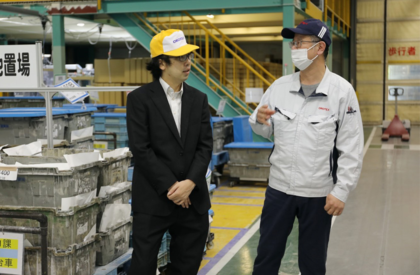 イイダ産業株式会社様の工場現場で話をしている富士通株式会社のSEの吉田と、イイダ産業株式会社様の水谷様の写真