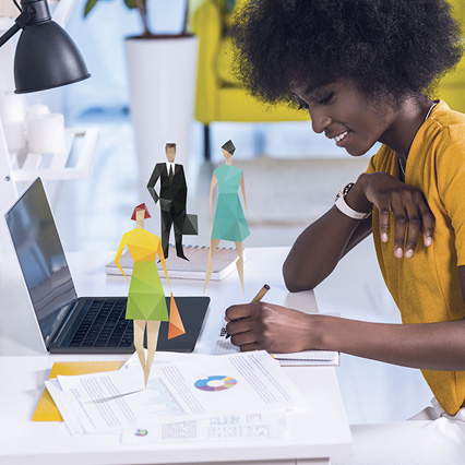 Woman writing notes on desk with origami figures