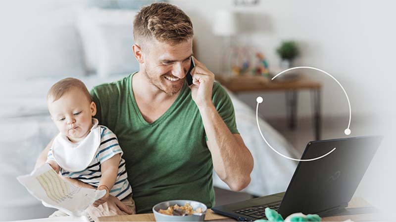 Photo of a person holding a baby and talking on the phone