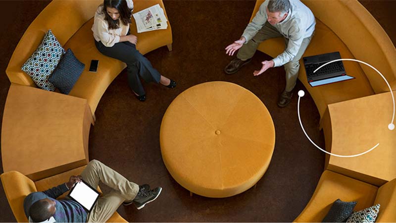 Photo of three people sat around a circular sofa talking