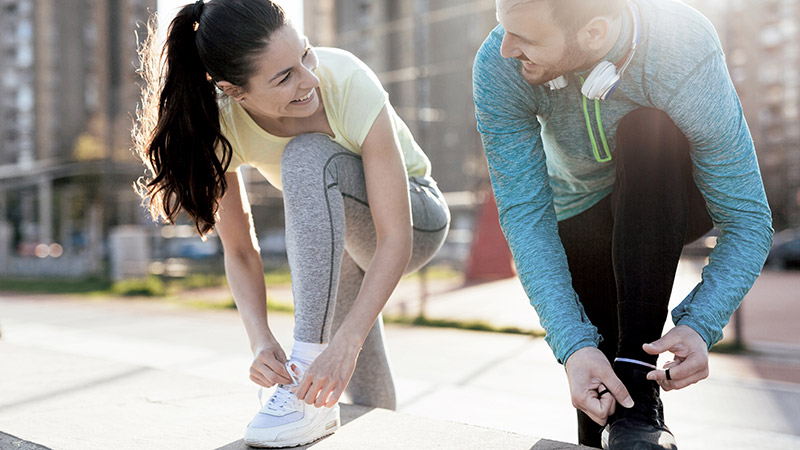 Two people tying their shoelaces before a run