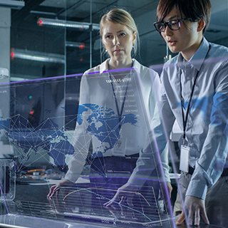 Two business women stood up working on a futuristic looking computer screen