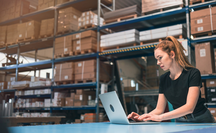 A woman who uses a laptop in a warehouse